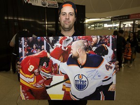 Tyler Osborne displays a photo of the Edmonton Oilers' Zack Kassian fighting the Calgary Flames' Matthew Tkachuk, which Kassian signed after the Oilers held an open practice inside West Edmonton Mall on Monday Jan. 27, 2020.