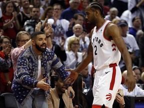 Toronto Raptors star Kawhi Leonard (2) gets a low five from Drake as he exits the game in Toronto, Ont. on Saturday April 27, 2019. (Jack Boland/Toronto Sun/Postmedia Network)