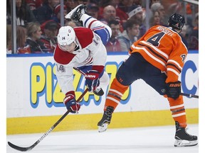 Montreal Canadiens' Nick Suzuki, left, is checked by Edmonton Oilers' Kris Russell during first period NHL hockey action in Edmonton, Saturday, Dec. 21, 2019.