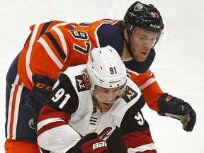 Arizona Coyotes Taylor Hall (front) is checked by Edmonton Oilers captain Connor McDavid during NHL hockey game action in Edmonton on Jan. 18, 2020.
