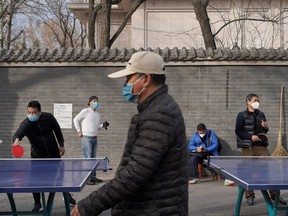 People wearing face masks play table tennis at a park, following an outbreak of the novel coronavirus in the country, in Beijing, Feb. 21, 2020. REUTERS/Stringer
