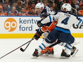 Edmonton Oilers' Tyler Ennis (63) is hauled down by Winnipeg Jets' Dmitry Kulikov (7) and Neal Pionk (4) during first period NHL hockey action at Rogers Place in Edmonton, on Saturday, Feb. 29, 2020.