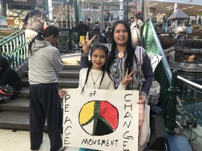 Michelle Alexis, right, stands with a Peace of Change sign just before a flash mob round dance took place at West Edmonton Mall on Saturday 22, 2020.