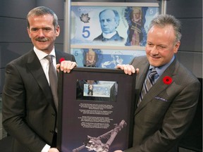 Canadian astronaut Chris Hadfield, left, presents Bank of Canada governor Stephen Poloz with the five dollar bill he took into space at a Canadian Space Agency ceremony to officially issue the new $5 polymer note on Nov. 7, 2013 in Longueuil, Que.