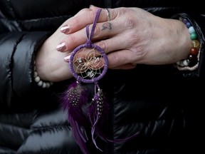 Marcy Oakes poses for a photo outside the Alberta Law Courts, in Edmonton Tuesday Feb. 4, 2020. Oakes is holding a dreamcatcher, made by her son, which she was keeping close to her during today's proceedings. A heart tattoo with her son's first initial is visible on her finger.