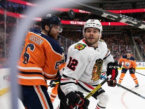 Adam Larsson (6) of the Edmonton Oilers and Alex DeBrincat (12) of the Chicago Blackhawks keep their eyes on the puck at Rogers Place on Feb. 11, 2020.