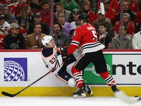 Connor Murphy (5) of the Chicago Blackhawks takes down Tyler Ennis (63) of the Edmonton Oilers along the boards at United Center on March 05, 2020, in Chicago.