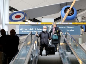 A traveller wearing a mask, amid rising global numbers of novel coronavirus disease (COVID-19) cases, arrives under a replica Nieuport 17 fighter plane at Billy Bishop Airport in Toronto, March 17, 2020. REUTERS/Chris Helgren