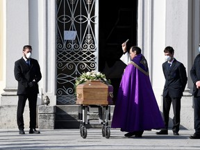 A priest blesses the coffin of a woman who died from coronavirus disease (COVID-19) at her funeral, as Italy struggles to contain the spread of coronavirus disease (COVID-19), in Seriate, Italy March 28, 2020. (REUTERS/Flavio Lo Scalzo)