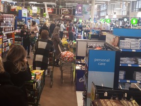 Shoppers wait in line at the Downtown Save-On-Foods shortly after noon Friday.