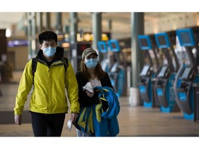 Passengers walk through the departure level at the Edmonton International Airport on Monday, March 16, 2020, in Edmonton.