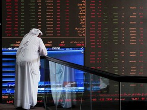 A trader checks stock prices at Boursa Kuwait in Kuwait City, as global oil markets plunged at the opening of markets on Monday.