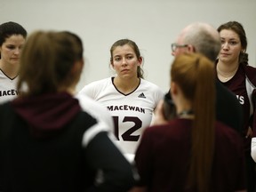 Kylie Schubert (12) listens to head coach Ken Briggs during a Canada West volleyball match between the MacEwan University Griffins and the University of Regina Cougars in Edmonton on Jan. 26, 2018.