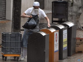 A person wearing a face mask as a preventive measure against the COVID-19 disease, takes out the trash in Vilanova i la Geltru on March 30, 2020.