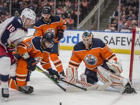 Goaltender Mikko Koskinen (19) of the Edmonton Oilers keeps his eye on the puck as it bounces around beside the net with Pierre-Luc Dubois of the Columbus Blue Jackets trying to get his stick loose at Rogers Place on Saturday, March 7, 2020.