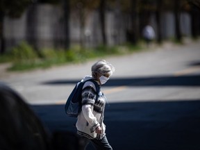 A woman wearing a fabric mask on her face walks in downtown Vancouver, on Thursday, April 16, 2020.