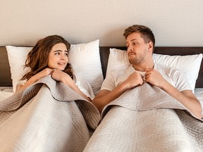 Young couple in the bed. Fear of sex, shy woman and man hidding under blanket before first intimacy