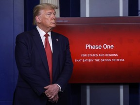U.S. President Donald Trump stands in front of a slide on a video monitor debuting "Phase One" of his administration's plans for "Opening Up America Again" during the daily coronavirus task force briefing at the White House in Washington, U.S., April 16, 2020. REUTERS/Leah Millis ORG XMIT: WAS462