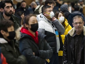 People wear masks as they wait for the arrivals at the International terminal at Toronto Pearson International Airport in Toronto on Saturday, January 25, 2020. Leaders of Toronto's Chinese community said Wednesday the racist attitudes that led to widespread discrimination against Chinese Canadians during the SARS epidemic are threatening to resurface during the current outbreak of a new coronavirus.