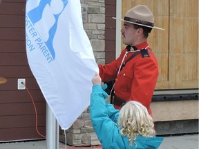 Const. Austin MacDougall and five-year-old Zoey LaPierre raise the Foster and Kinship Week flag Oct. 17, 2016 at Centennial Park in Edson, Alta. MacDougall, an RCMP officer, was riding his bike while off duty on Range Road 181 west of Edson when he was struck by a vehicle and killed around 9 p.m. on Wednesday, July 5, 2017.