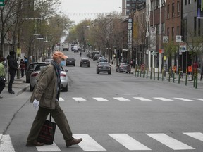 A man wearing a mask crosses street on St-Laurent Blvd. during COVID-19 pandemic on May 15, 2020.