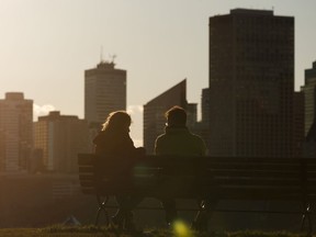 A couple take a moment on a bench looking towards downtown at Gallagher Park near sunset on a warm spring day in Edmonton, on Friday, May 8, 2020.