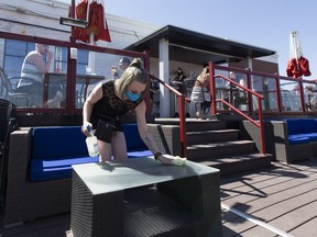 Spotlight Cabaret server,Taylor Cherryholme disinfects tables on the restaurants roof-top patio on May 16, 2020, in Edmonton. Greg Southam/Postmedia