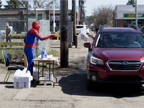 Dressed as Spider-Man, James Steer uses a pole to deliver bags of comic books to drive-thru customers during Free Comic Book Day at Warp 1 Comics and Games, 9917 82 Ave., in Edmonton on May 2, 2020. Steer had to use the unorthodox delivery system due to COVID-19 restrictions and sanitized the pole after each customer.
