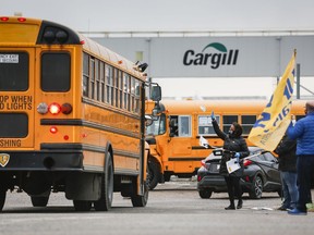 Union representatives wave at a shuttle bus carrying workers returning on Monday, May 4, 2020, to the Cargill beef processing plant in High River, Alta., after it was closed for two weeks because of COVID-19.