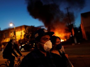 People walk in front of burning cars during a demonstration against the death in Minneapolis police custody of African-American man George Floyd, in Minneapolis, Minnesota, U.S., May 29, 2020.