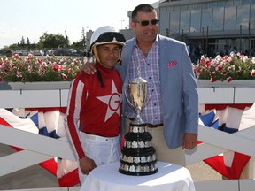 Jockey Orlando Mojica (left) and trainer Robertino Diodoro pose with the trophy after Mojica rode Oil Money to victory in the Manitoba Derby at Assiniboia Downs on Aug. 5, 2019.