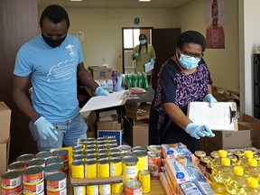 Volunteers Edward Jalaji (left) and Theresa Chakanyuka put together food hampers at the Africa Centre.