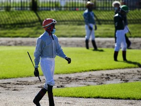 Jockeys enter the paddock wearing masks before the first race on opening day of the season for Century Mile Racetrack on Sunday, June 21, 2020. No fans were allowed in the stands, just jockeys, horses and trainers.
