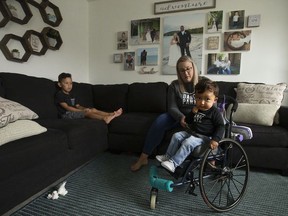 Lana Bernardin helps her son Kaysen Martin, 1, into the family living room, in Edmonton Thursday July 2, 2020. Her oldest son Blake Martin, 4, is also pictured (left). Kaysen has a rare motor neuron disease called Spinal Muscular Atrophy Type 1 (SMA 1). His family has met all approvals to get a new drug called Zolgensma administered to help keep Martin alive and healthy, but it costs $2.8 million and isn't covered in Alberta.