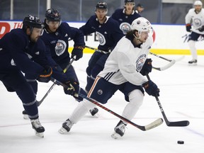Kaiser Yamamoto (56) is chased by Kris russell (4), Ethan Bear (74), and Connor McDavid (97) during an Edmonton Oilers training camp scrimmage in Edmonton on Wednesday, July 22, 2020.