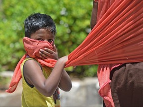 In this picture taken on July 8, 2020, a boy covers his face with the scarf of his mother as he walks along the road after the government eased a nationwide lockdown imposed as a preventive measure against the COVID-19 coronavirus, in Chennai, India.