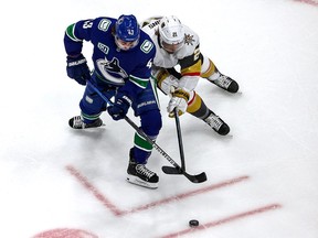 Quinn Hughes #43 of the Vancouver Canucks and Nick Cousins #21 of the Vegas Golden Knights battle for the puck during the first period in Game 3 of the Western Conference Second Round during the 2020 NHL Stanley Cup Playoffs at Rogers Place on August 29, 2020.