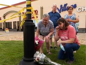 (Left to right) Nora Gueffroy, Janelle Bulloch, Lisa Tory and Les Gueffroy placed flowers as RCMP officers investigate a homicide at the Village Mall Clinic in Red Deer, Aug. 10, 2020.