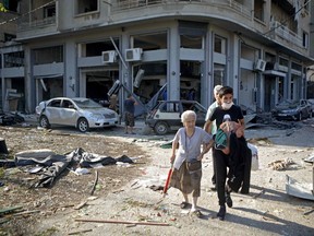 A woman is evacuated from the partially destroyed Beirut neighbourhood of Mar Mikhael.