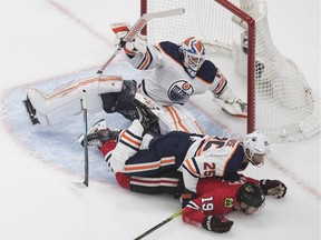 Edmonton Oilers goalie Mikko Koskinen (19) is crashed into by Chicago Blackhawks' Jonathan Toews (19) and Oilers' Darnell Nurse (25) during NHL qualifying round game action in Edmonton, on Friday Aug. 7, 2020.