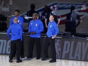 Officials stand beside an empty court before the scheduled start of Game 5 between the Magic and Bucks in the first round of the 2020 NBA Playoffs at ESPN Wide World Of Sports Complex in Lake Buena Vista, Fla., on Wednesday, Aug. 26, 2020.