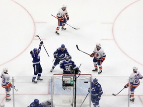 Ondrej Palat (18), Andrei Vasilevskiy (88) and Barclay Goodrow (19) of the Tampa Bay Lightning celebrate their 2-1 victory as Mathew Barzal (13) of the New York Islanders skates away in Game 2 of the Eastern Conference final of the 2020 NHL Stanley Cup Playoffs at Rogers Place on Wednesday, Sept. 09, 2020.