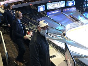 With no fans at Rogers Place, Sportsnet colour commentator Louie DeBrusk, left, play-by-play voice Chris Cuthbert and in-game stats man David Moir call an NHL playoff game from their makeshift booth in the seating area instead of higher up in the press box.