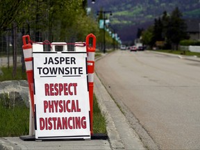 In this file photo taken in June, a sign to the entrance of the main street in downtown Jasper, Alberta reminds visitors of the global COVID-19 pandemic.