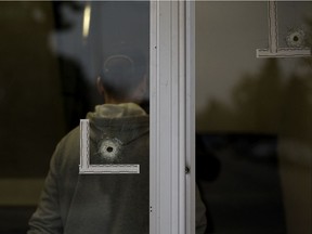 Two bullet holes are visible in the front door of an apartment building at 9604 129B Ave., in Edmonton Monday Oct. 19, 2020.