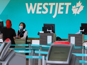 A WestJet employee checks in a passenger at the Calgary International Airport on Wednesday, June 24, 2020. WestJet announced it will end flights to many eastern Canadian locations this November.