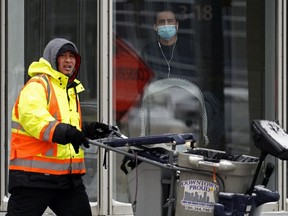 A man keeps warm inside the Bell Tower in downtown Edmonton as a street sanitation worker passes by outside on Thursday, Nov. 19, 2020.