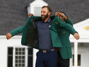 Dustin Johnson is presented with the green jacket by Tiger Woods after winning the Masters on Sunday.