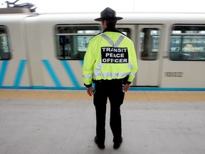 A transit peace officer watches an LRT train pull out of the Century Park South LRT station. City peace officers could be called on to help enforce new provincial COVID-19 restrictions.
