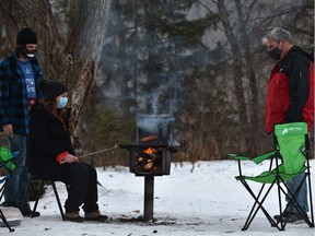 Christmas Day cookout as Amy Conner roasts some smokies over the open flame as her boyfriend Tim Frison and her father John Conner look on at Hawrelak Park in Edmonton, December 25, 2020.